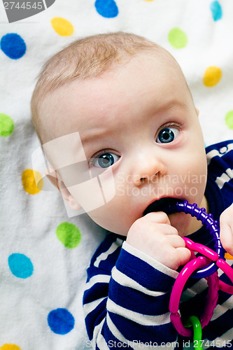 Image of cute baby in striped clothes lying down on a blanket