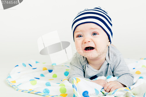 Image of cute baby in striped hat lying down on a blanket