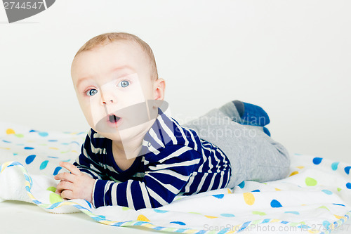 Image of cute baby in striped clothes lying down on a blanket