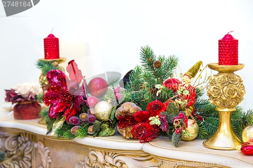 Image of A fireplace mantle is decorated for Christmas with garland, ligh