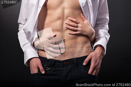 Image of Woman's hands on a sexy man's torso