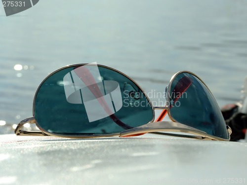 Image of The sunglasses laying on a white surface on a background of wate