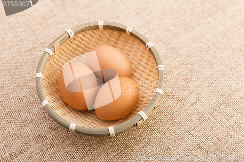 Image of Egg in basket over linen background