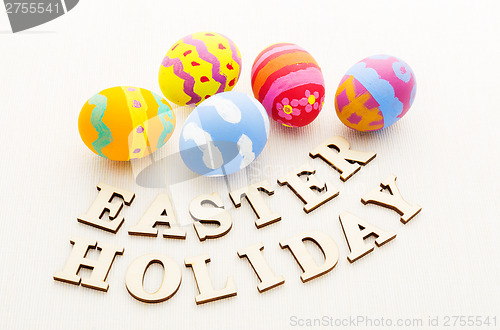 Image of Kid drawing easter egg with wooden text