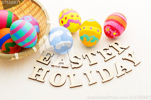 Image of Colourful easter egg in basket with wooden text 