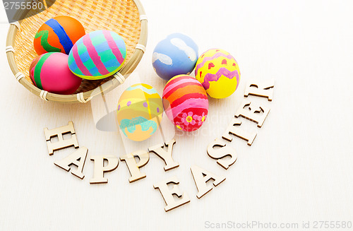 Image of Colourful easter egg in basket with wooden text