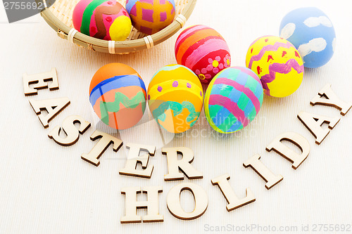 Image of Colourful easter egg in basket with wooden text
