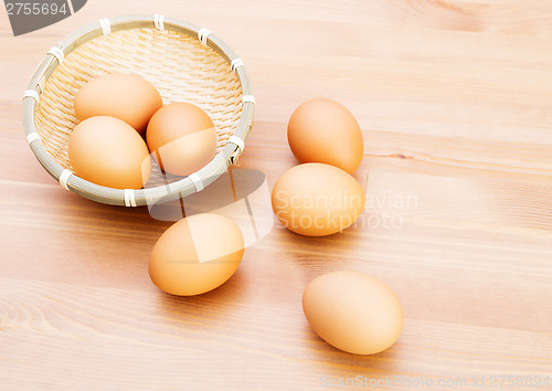 Image of Brown egg in basket over wooden texture