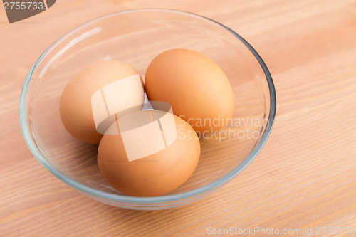 Image of Brown egg in bowl over wooden background
