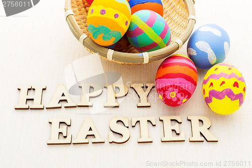 Image of Colourful painted easter egg in basket with wooden text 