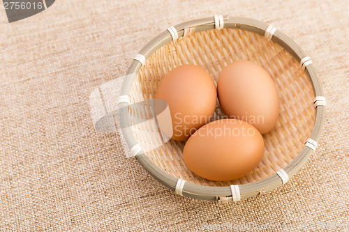 Image of Brown egg in basket over linen background