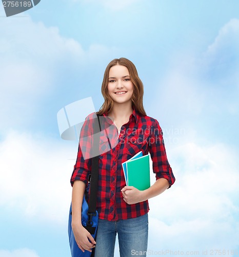 Image of smiling female student with bag and notebooks