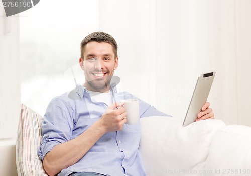 Image of smiling man working with tablet pc at home