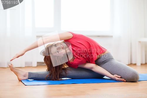 Image of smiling teenage girl streching on floor at home