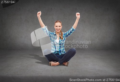 Image of young woman in casual clothes sitting on floor