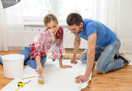 Image of smiling couple smearing wallpaper with glue