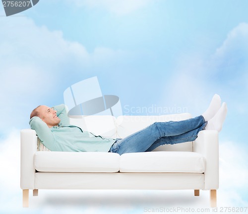 Image of smiling man lying on sofa