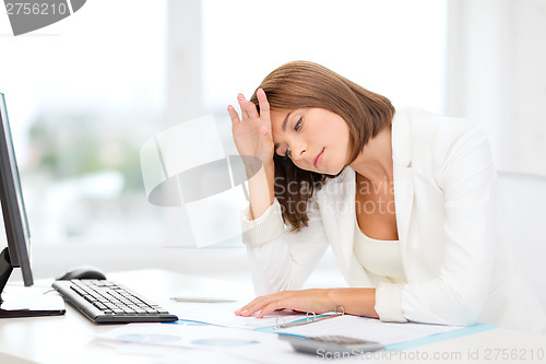 Image of tired businesswoman with computer and papers