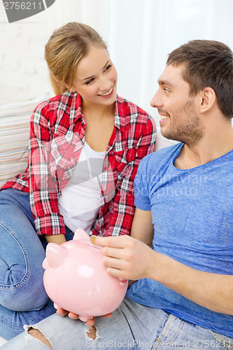 Image of smiling couple with piggybank sitting on sofa