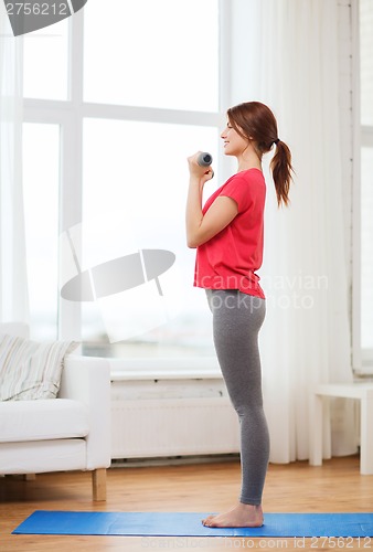Image of smiling teenage girl exercising with dumbbells