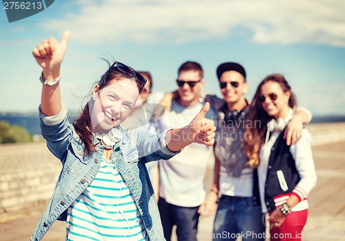 Image of teenage girl with headphones and friends outside