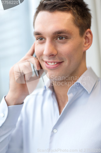 Image of smiling businessman with smartphone in office