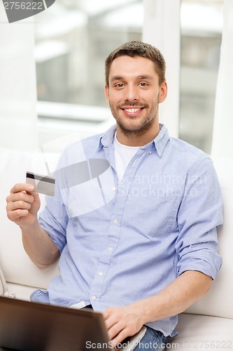 Image of smiling man working with laptop and credit card