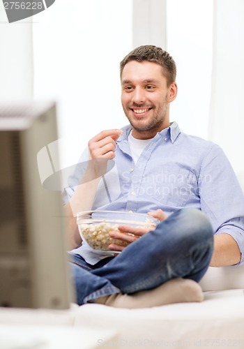 Image of smiling man watching sports at home