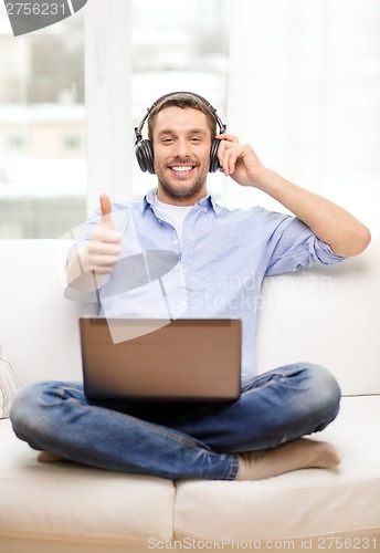 Image of smiling man with laptop and headphones at home