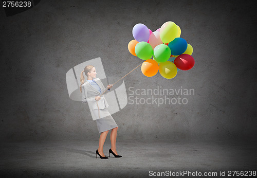 Image of smiling businesswoman pulling rope with balloons