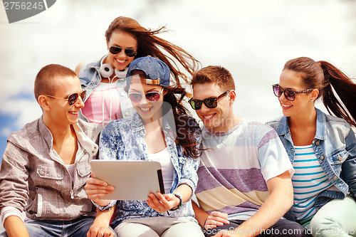 Image of group of smiling teenagers looking at tablet pc