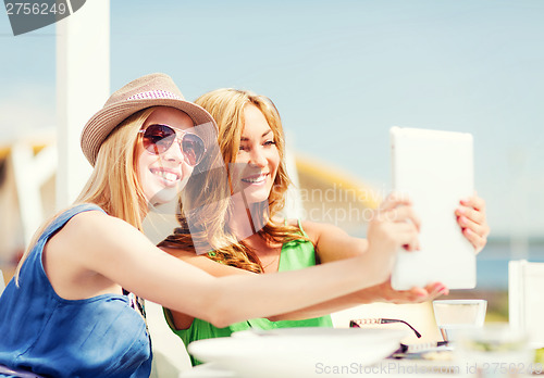 Image of girls taking photo in cafe on the beach