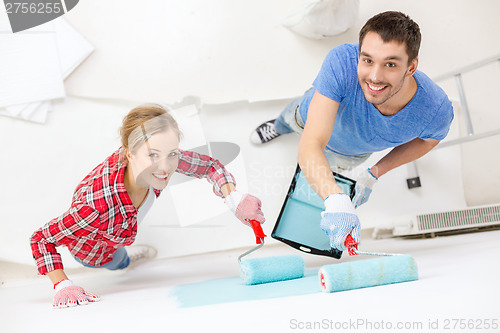 Image of smiling couple painting wall at home