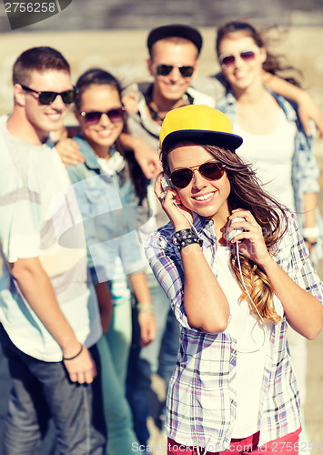 Image of teenage girl with headphones and friends outside