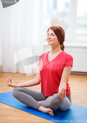 Image of smiling redhead teenager meditating at home