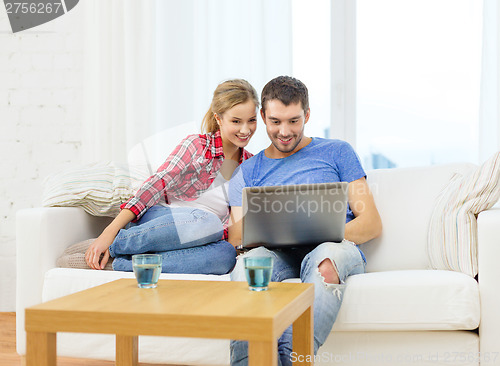 Image of smiling couple with laptop computer at home