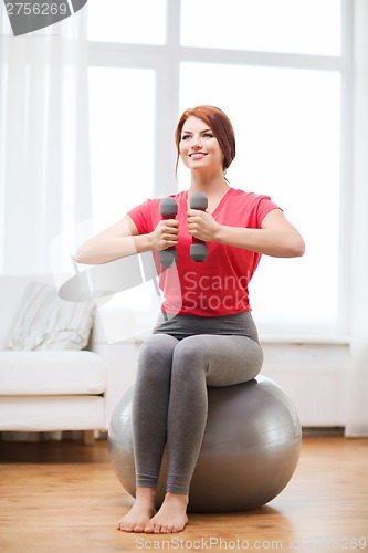 Image of smiling redhead girl exercising with fitness ball