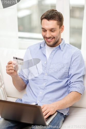 Image of smiling man working with laptop and credit card