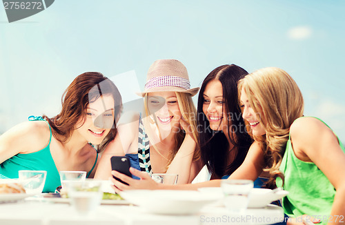 Image of girls looking at smartphone in cafe on the beach