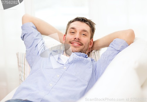 Image of smiling man lying on sofa at home