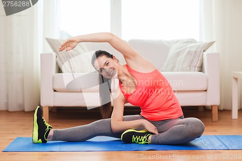 Image of smiling teenage girl streching on floor at home