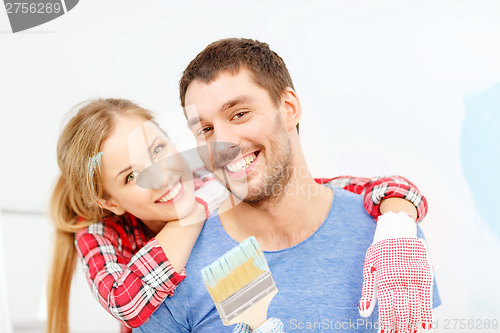 Image of smiling couple covered with paint with paint brush