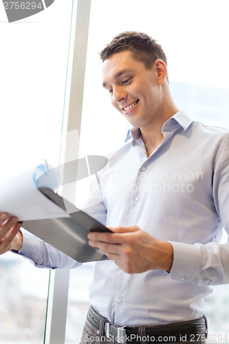 Image of smiling businessman with clipboard in office