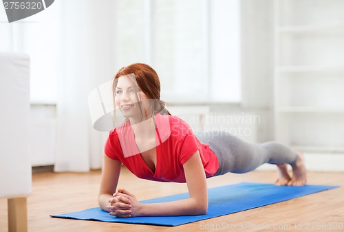 Image of smiling redhead teenage girl doing plank at home