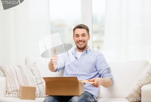 Image of man with cardboard boxes at home showing thumbs up