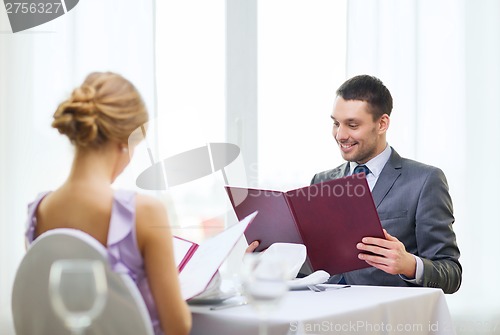 Image of smiling young man looking at menu at restaurant