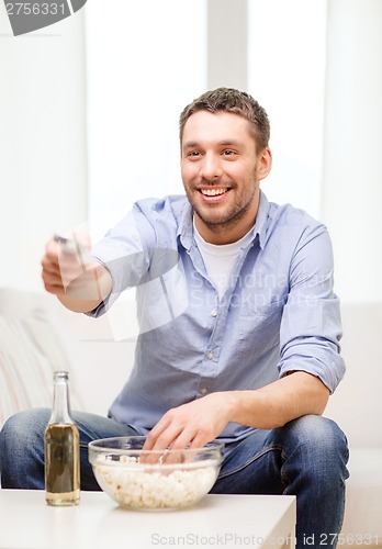 Image of smiling man with tv remote control at home