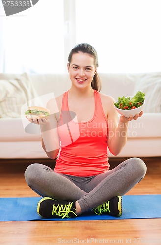 Image of smiling teenager with green salad and hamburger