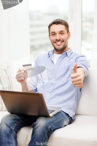 Image of smiling man working with laptop and credit card