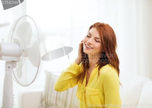 Image of smiling redhead teenage girl with big fan at home